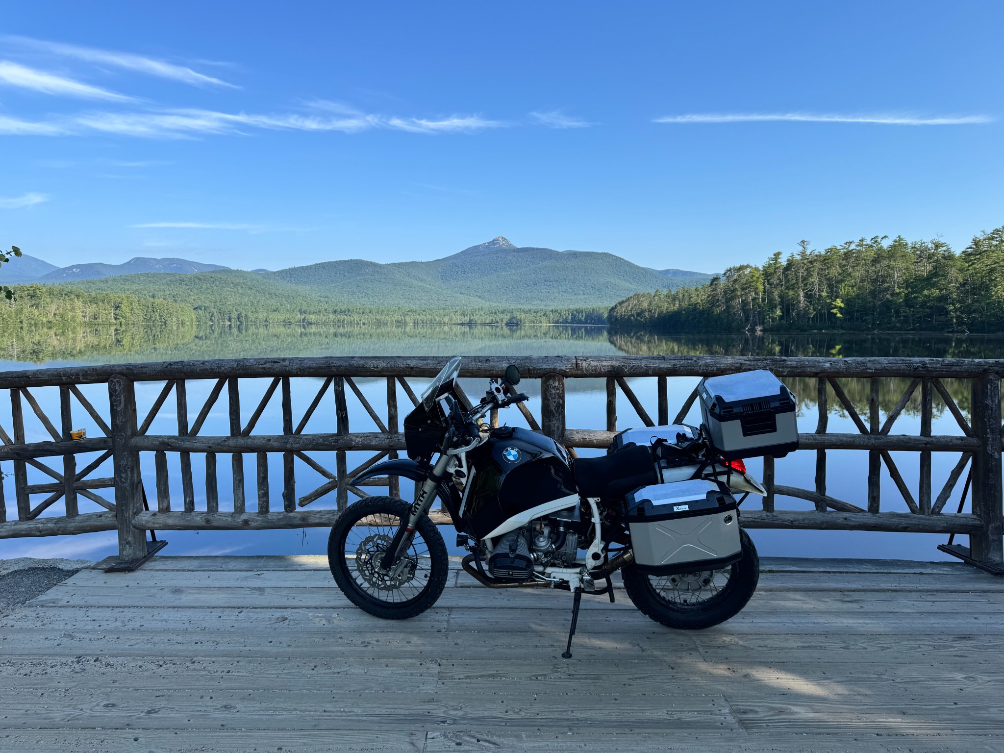 Black and white BMW R80ST parked on a timber bridge at Lake Chocorua with Mount Chocorua reflected in the water
